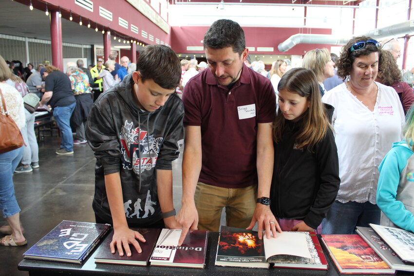 Class of 1997 graduate Brian Sanders, center, reviews Golden High School yearbooks with his family during the school's 150th anniversary celebration on June 4.